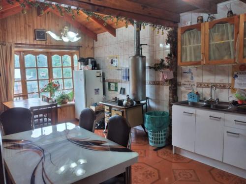 a kitchen with a table with chairs and a refrigerator at Hostal Tintica Buey Puerto Fuy in Puerto Fuy