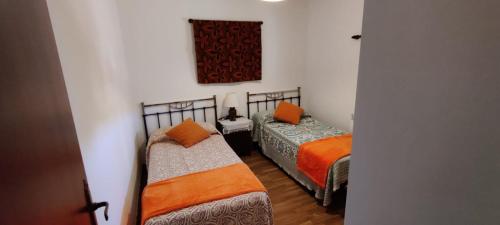 Habitación con 2 camas y almohadas de color naranja. en Casa El Rostro, en Aldeadávila de la Ribera