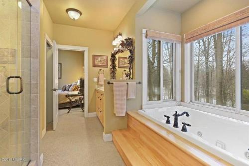 a large bathroom with a tub and a window at Woodshores Retreat - cozy retreat, hot tub, Lk MI in Coloma