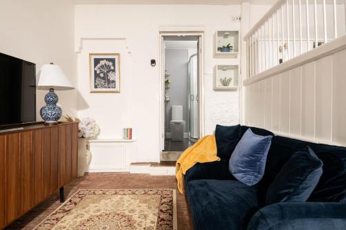 a living room with a blue couch and a television at The Stable—Historic Property in Downwood Vineyard in Blandford Forum