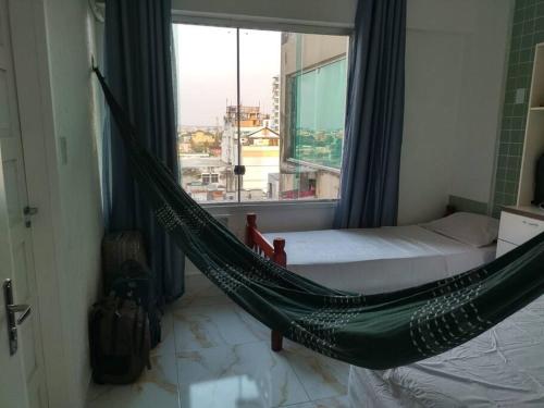 a hammock in a room with a large window at Joia Centro Manaus - Apartamento in Manaus