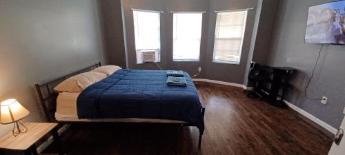 a bedroom with a bed with a blue blanket and two windows at Willoughby in Newark