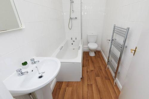 a bathroom with a sink and a tub and a toilet at Derby central 4 bed house - Free parking in Derby