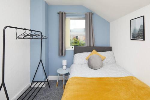 Derby central 4 bed house - Free parking في ديربي: غرفة نوم بسرير وبطانية صفراء