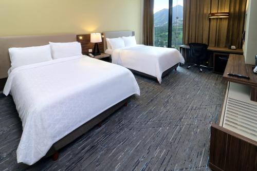 a hotel room with two beds and a desk at Holiday Inn Express & Suites Monterrey Valle by IHG in Monterrey