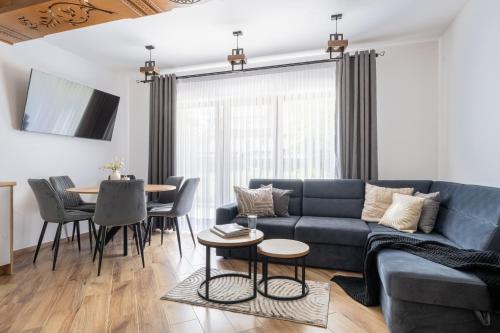 a living room with a blue couch and a table at Para Apartments - Dwupoziomowe Apartamenty in Biały Dunajec