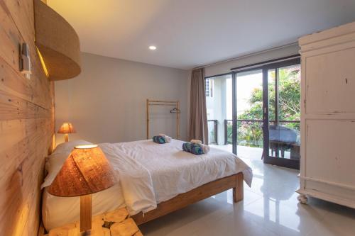 a bedroom with a bed and a large window at Surf House Santai Villa Balian in Tabanan