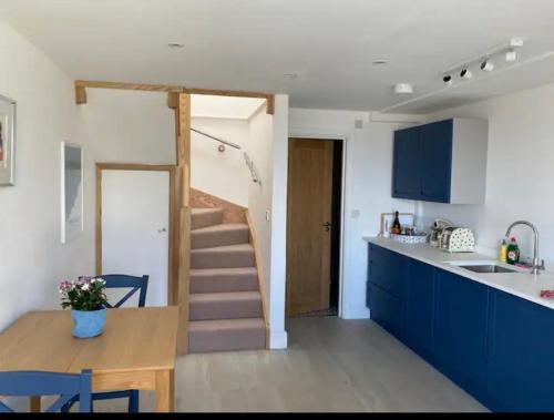 una cocina con armarios azules y una escalera en una habitación en Stunning little house, 2 mins from Lyme Regis beach with a sea view to die for. Sleeps 2, free parking, small dog welcome., en Lyme Regis