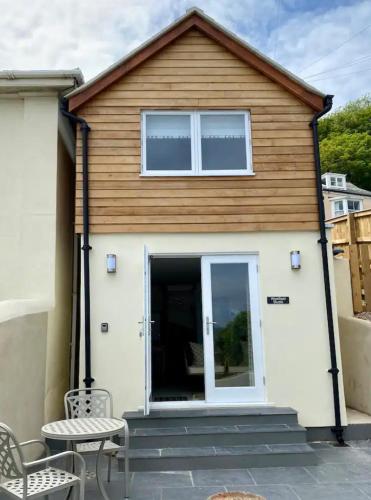 una casa con puerta, mesa y sillas en Stunning little house, 2 mins from Lyme Regis beach with a sea view to die for. Sleeps 2, free parking, small dog welcome., en Lyme Regis