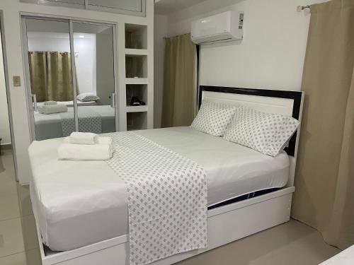 a white bedroom with a bed and a mirror at Plataview Apartahotel apt 4A in Monte Plata