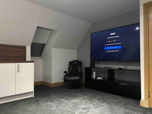 a living room with a large screen tv and a chair at 101 Scotia Rooms in South Cobbinshaw
