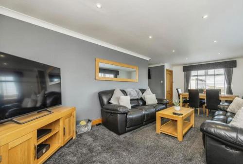 101 Scotia Rooms : غرفة معيشة مع أريكة جلدية سوداء وتلفزيون بشاشة مسطحة