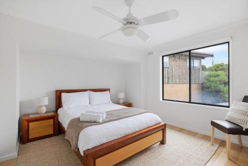 a bedroom with a bed and a window and a chair at Deckchairs in Smiths Beach