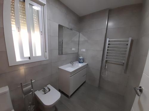 a bathroom with a sink and a toilet and a window at Puerta de la Bética in Mengibar