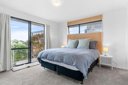 a bedroom with a large bed with a large window at The Summer Pad - Omaha Holiday Home in Warkworth