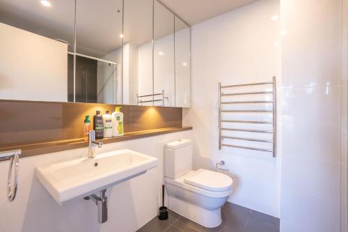 ein Badezimmer mit einem Waschbecken, einem WC und einem Spiegel in der Unterkunft Olympic Park 2 Bedrooms Charm Family Friend Free Parking in Sydney