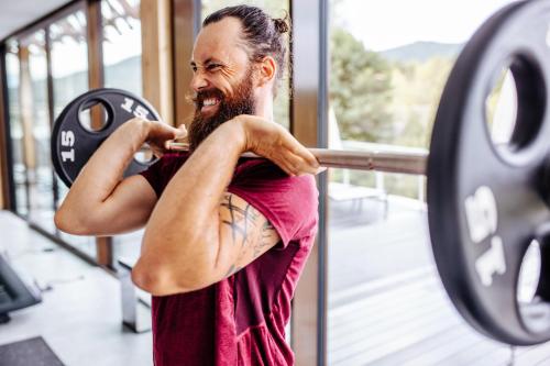 a man lifting a bar at a gym at Das Seepark Wörthersee Resort in Klagenfurt