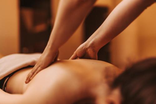 a woman getting a back massage in a salon at Das Seepark Wörthersee Resort in Klagenfurt