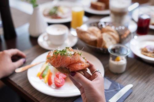 a person holding up a piece of food on a table at Das Seepark Wörthersee Resort in Klagenfurt