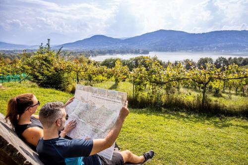 a man and woman sitting on a bench looking at a map at Das Seepark Wörthersee Resort in Klagenfurt