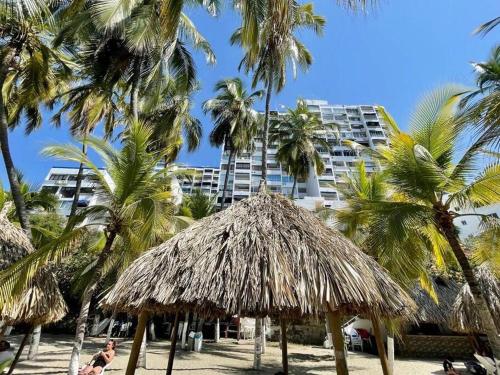 a man sitting on a beach with palm trees and a building at Perla Santa - Luxury Condo in Santa Marta