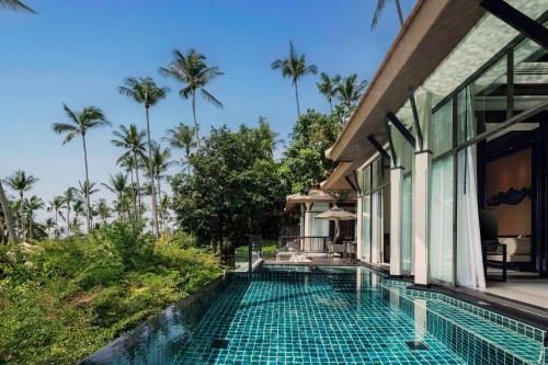 an infinity pool in front of a house with palm trees at Banyan Tree Samui in Lamai