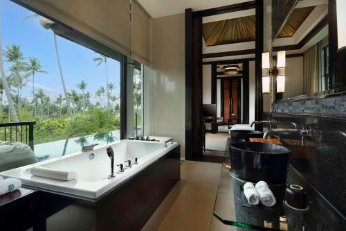 a bathroom with a large bath tub with a large window at Banyan Tree Samui in Lamai