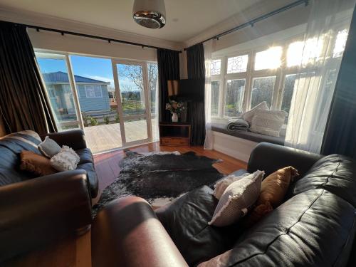 a living room with a leather couch and windows at Pinot Villas in Martinborough 