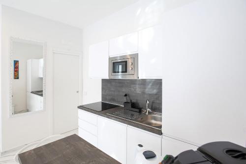 a white kitchen with a sink and a microwave at Tema Suites in Naples