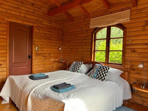 1 dormitorio con 1 cama en una cabaña de madera en Zapato Amarillo Bed & Breakfast, en Puerto Octay
