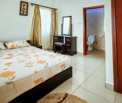 ein Schlafzimmer mit einem Bett und ein Badezimmer mit einem WC in der Unterkunft Lovely 2-bedroom house near Aburi in Accra