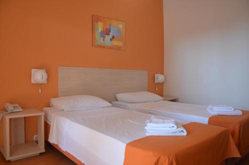 2 camas en una habitación con paredes de color naranja en Hotel Borik, en Lumbarda