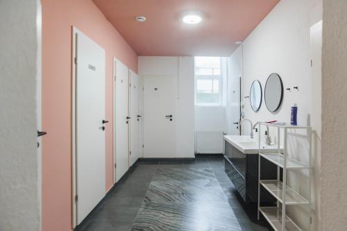 Baño con 2 lavabos y pared rosa en Malfatti Room Oasis with coworking space, en Viena