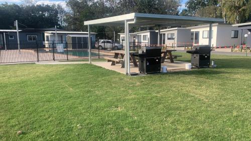a picnic shelter with benches and trash cans in a park at Yandina Caravan Park in Yandina
