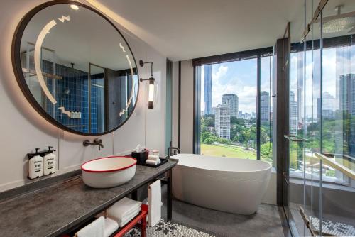 a bathroom with a tub and a large mirror at Hotel Indigo Kuala Lumpur on the Park by IHG in Kuala Lumpur