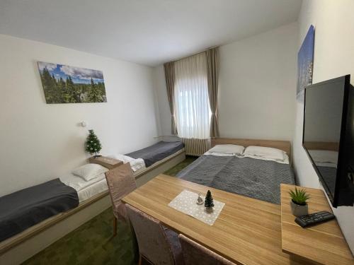 コパオニクにあるApartments Konaci Kopaonikのベッド2台とテーブルが備わる小さな客室です。