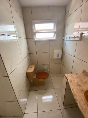 a small bathroom with a toilet and a window at Pousada Puerta Del Sol Rio das Ostras in Rio das Ostras