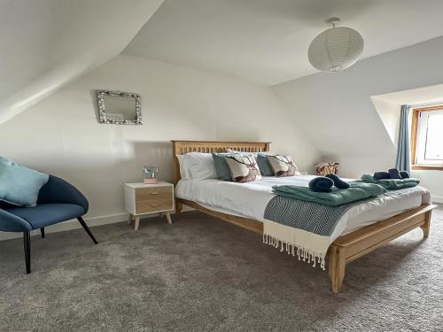 um quarto com uma cama e uma cadeira azul em Tigh Na Mara em Helmsdale