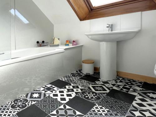 uma casa de banho com lavatório e piso em azulejo preto e branco em Tigh Na Mara em Helmsdale