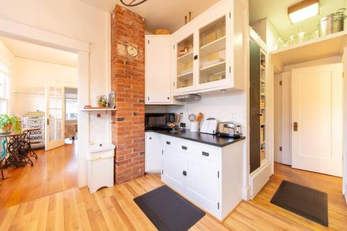 a kitchen with white cabinets and a brick wall at Manitou Springs White Yarrow Inn House in Manitou Springs