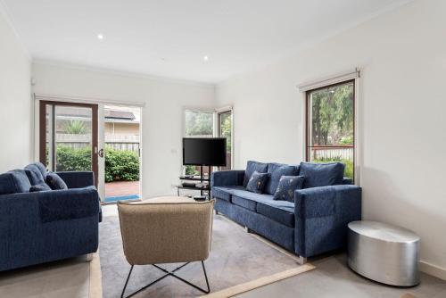 a living room with two blue couches and a tv at Bayti Retreat in Queenscliff