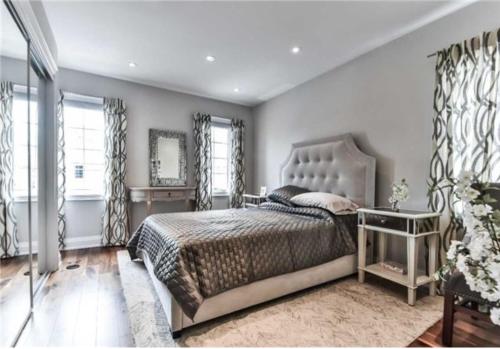 a bedroom with a bed and a mirror and windows at Immaculate Executive Townhouse 3Br&3Ba at Lawrence Park in Toronto