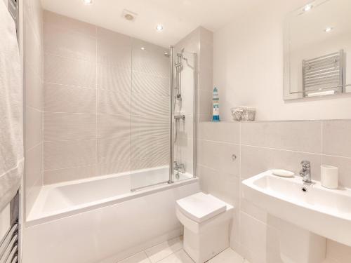 een witte badkamer met een douche, een toilet en een wastafel bij Whinstone House in Craster