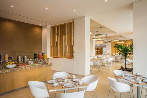 a dining room with tables and white chairs at Fiesta Inn Silao Puerto Interior in Silao
