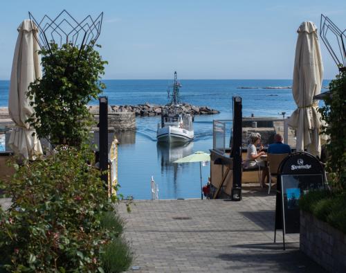 a boat is docked at a marina with people sitting at a table at Hotel Siemsens Gaard in Svaneke
