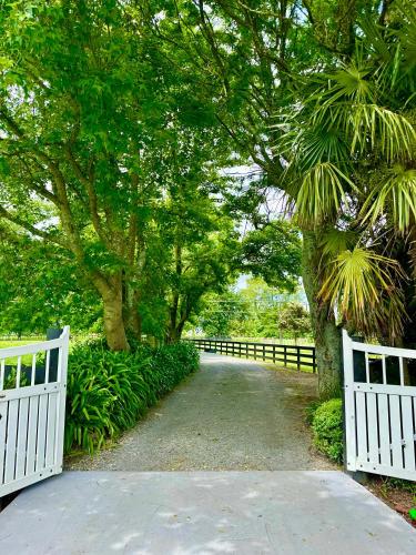 a pathway with two white fences and trees at Matamata Country B&B in Matamata