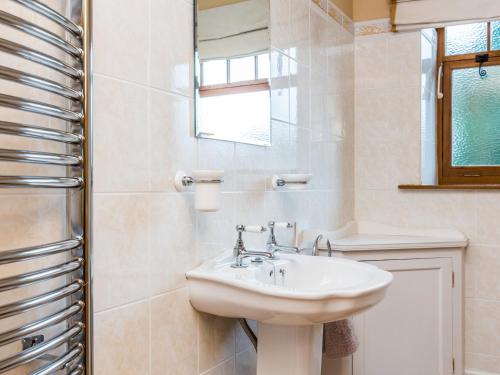ein weißes Badezimmer mit einem Waschbecken und einem Spiegel in der Unterkunft Anvil Cottage in Biscathorpe