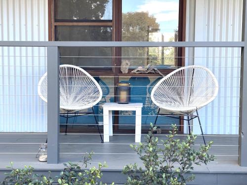 two white chairs and a table on a porch at Hannah's Place in the heart of Lovedale, Hunter Valley wine country, Free bottle of wine with each booking in Lovedale