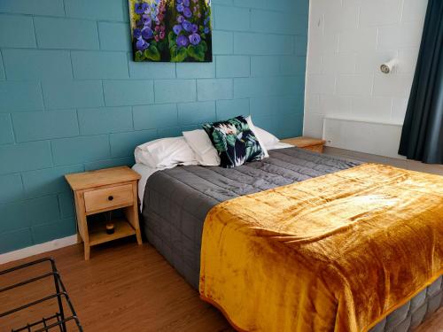 a bedroom with a bed with a blue wall at Aarangi Tui Motel in Paihia