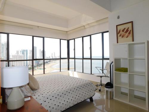 a bedroom with a bed and large windows at Apartamento Luxury frente al mar in Cartagena de Indias